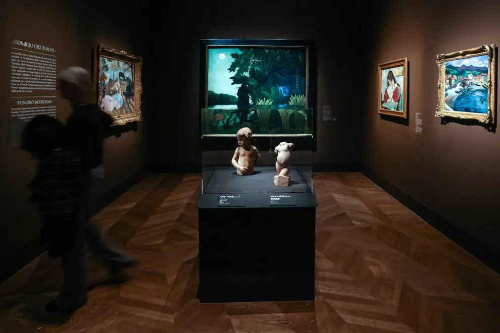 Un hombre camina junto a las obras de arte tituladas 'Busto de niño', 'Busto de niña', del pintor francés Albert Marquet, y El encantador de serpientes (La Charmeuse de serpents), del pintor francés Enrique Rousseau