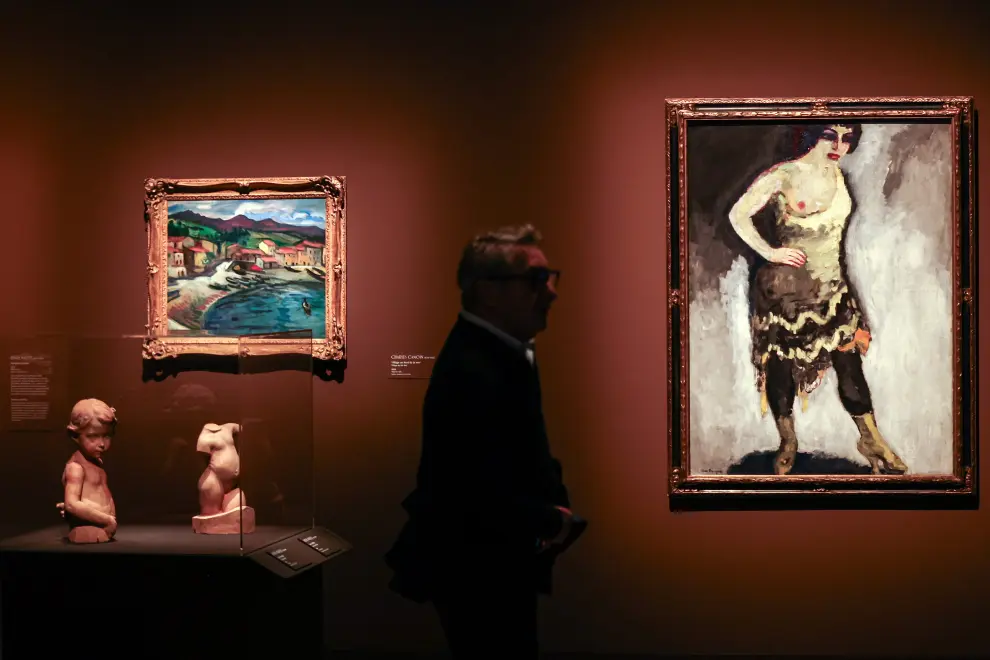 Un hombre camina junto a las obras de arte tituladas 'Nini, bailarina en el Folies-Bergères' del pintor holandés-francés Kees van Dongen, y 'Pueblo junto al mar' del pintor francés Charles Camoin