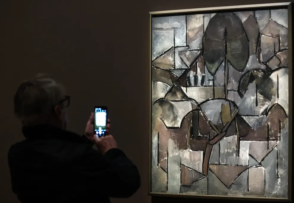 Un hombre toma una fotografía de una obra de arte titulada 'Paisaje con árbol' de Piet Mondrian