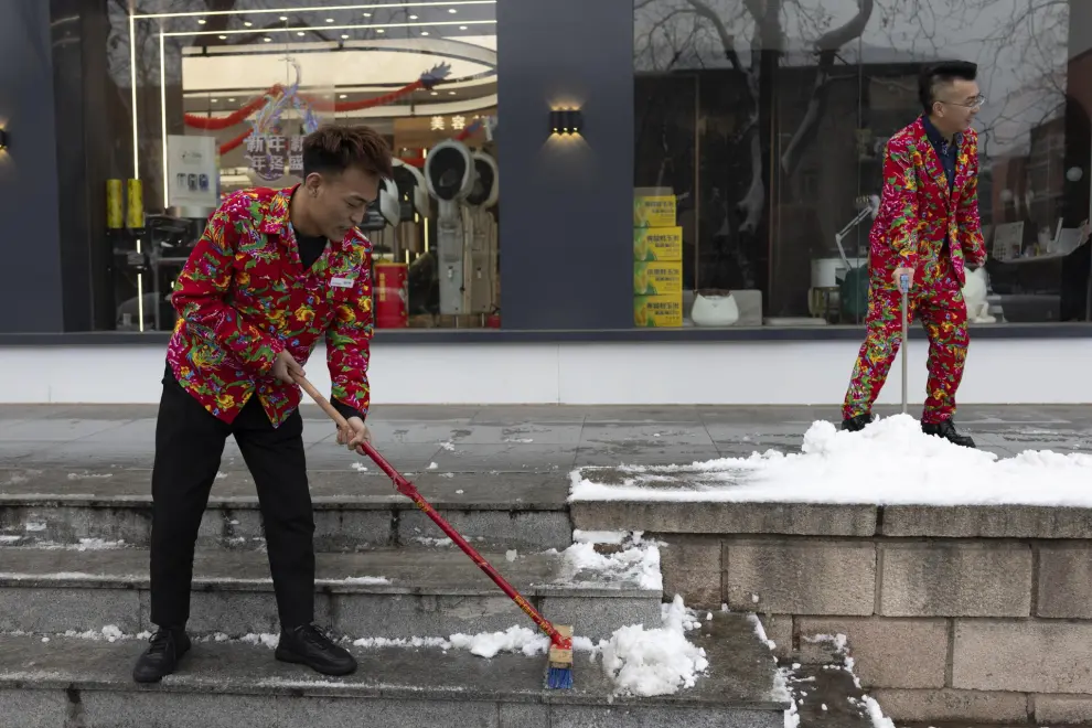 Beijing (China), 11/12/2023.- Workers at a beauty hair salon remove snow from small steps in Beijing, China, 11 December 2023. Beijing has its first snowfall this winter as in the northern regions, China'Äôs Meteorological service has issued a yellow alert for blizzards. EFE/EPA/ANDRES MARTINEZ CASARES
