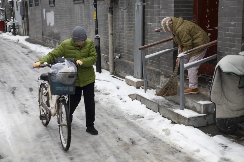 Beijing (China), 11/12/2023.- A woman pushes her bicycle along a street covered in snow in Beijing, China, 11 December 2023. Beijing has its first snowfall this winter as in the northern regions, China'Äôs Meteorological service has issued a yellow alert for blizzards. EFE/EPA/ANDRES MARTINEZ CASARES
