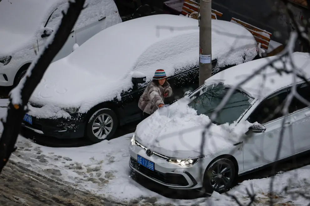 Beijing (China), 11/12/2023.- A woman removes snow from her car in Beijing, China, 11 December 2023. Beijing received its first snowfall as China's National Meteorological Center issued a yellow alert for heavy snowfall in the northern regions of the country. EFE/EPA/MARK R. CRISTINO