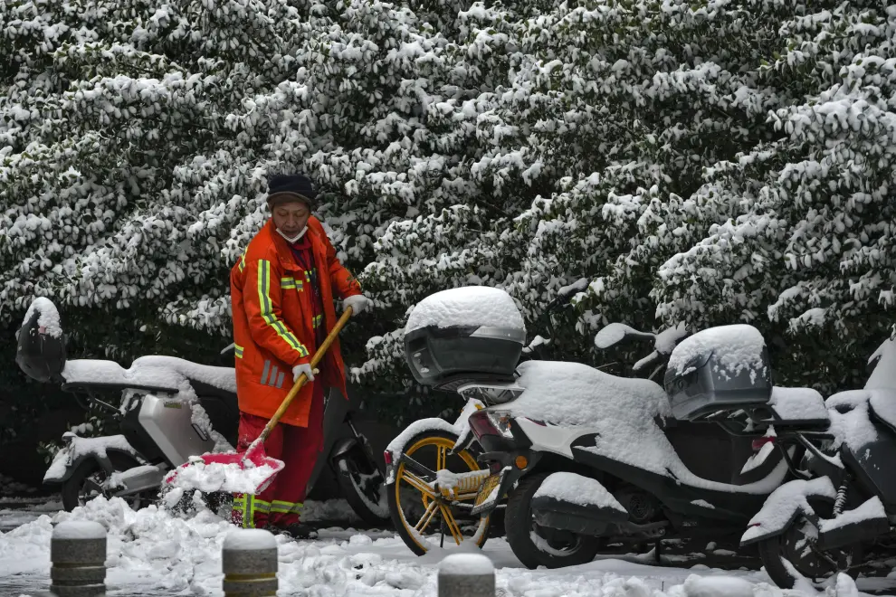 A city worker clears the snow covered pathway after a snow fall hit the capital city in Beijing, Monday, Dec. 11, 2023. An overnight snowfall across much of northern China prompted road closures and the suspension of classes and train service on Monday.(AP Photo/Andy Wong)