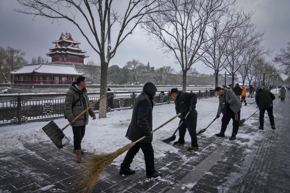 City workers clear the snow on a pathway near the Forbidden City after a snow fall in Beijing, Monday, Dec. 11, 2023. An overnight snowfall across much of northern China prompted road closures and the suspension of classes and train service on Monday.(AP Photo/Andy Wong)