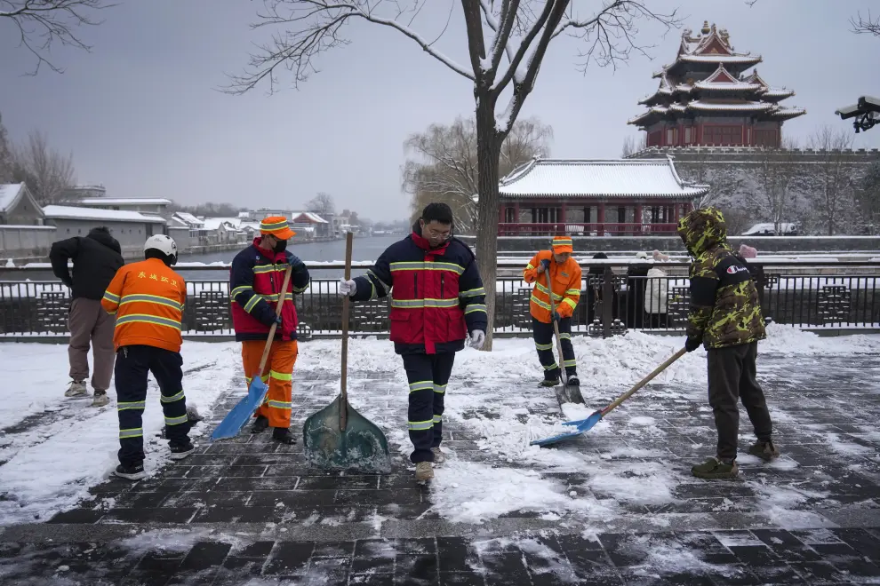 City workers clear the snow on a pathway near the Forbidden City after a snow fall in Beijing, Monday, Dec. 11, 2023.  An overnight snowfall across much of northern China prompted road closures and the suspension of classes and train service on Monday.(AP Photo/Andy Wong)