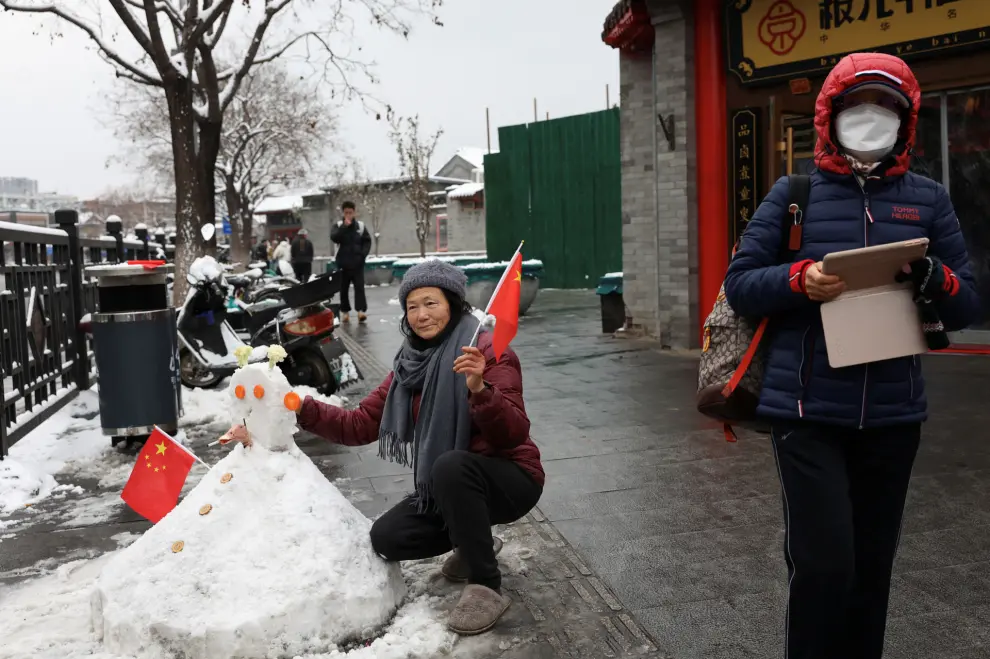 A person holding a Chinese national flag poses next to a snowman for pictures on a snowy day in Beijing, China December 11, 2023. REUTERS/Tingshu Wang [[[REUTERS VOCENTO]]]