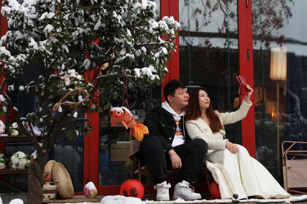 A couple poses with their marriage certificate during a photo shooting session on a snowy day in Beijing, China December 11, 2023. REUTERS/Tingshu Wang [[[REUTERS VOCENTO]]]