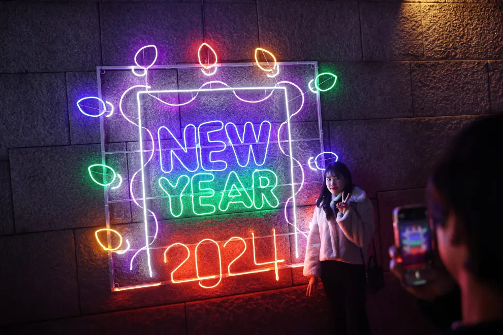 Una mujer posa para fotografías con un cartel luminoso de 2024 en Seúl