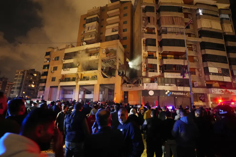 People gather outside a damaged building following a massive explosion in the southern Beirut suburb of Dahiyeh, Lebanon, Tuesday, Jan. 2, 2024. An explosion killed Saleh Arouri, a top official with the Palestinian militant group Hamas and three others, officials with Hamas and the Lebanese group Hezbollah said. (AP Photo/Bilal Hussein)