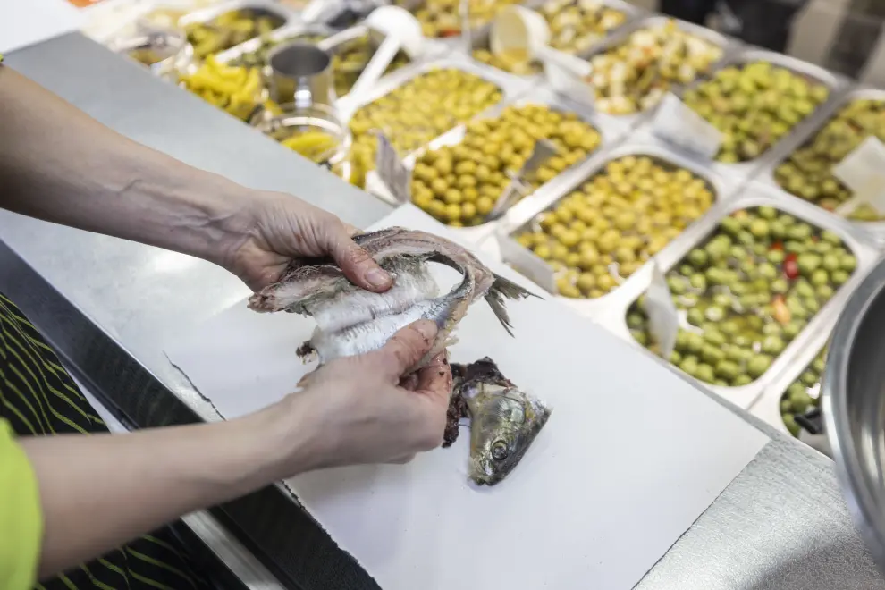 Sofía muestra cómo se limpia una sardina en Hermanos Rezusta, en el Mercado Central de Zaragoza.