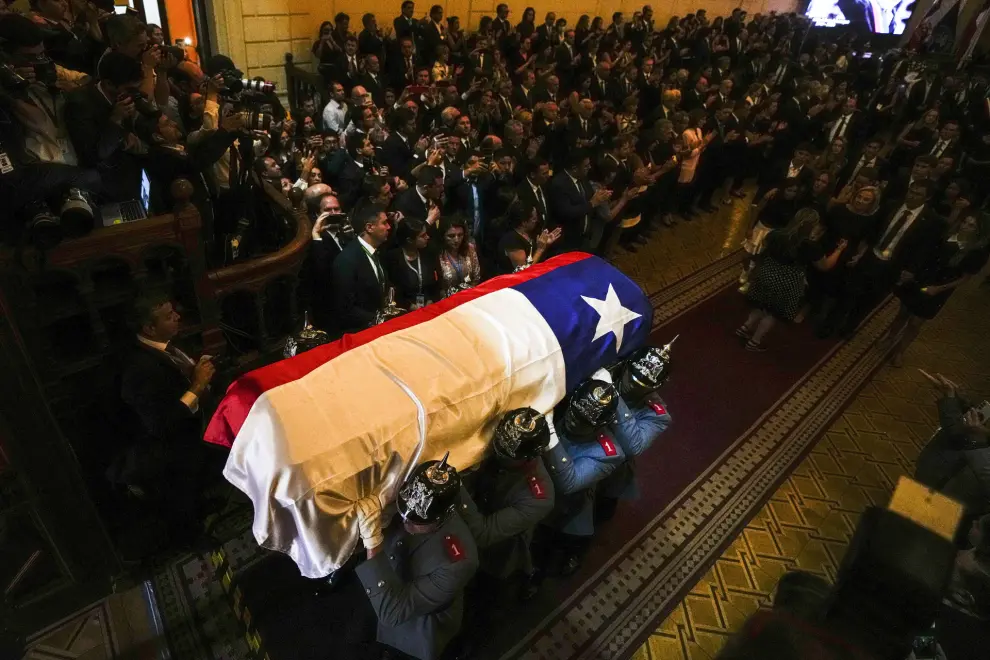 The flag-draped coffin of former Chilean President Sebastian Pinera is carried by honor guards out of Congress to La Moneda presidential palace in Santiago, Chile, Friday, Feb. 9, 2024. The two-time former president died on Feb. 6 in a helicopter crash. He was 74. (AP Photo/Esteban Felix)
