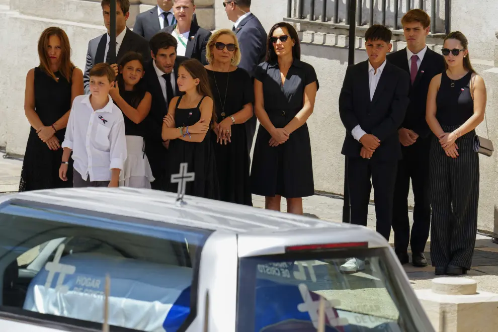 The relatives of late Chilean President Sebastian Pinera stand outside La Moneda presidential palace as the hearse carrying his remains drive to the cemetery during his state funeral procession in Santiago, Chile, Friday, Feb. 9, 2024. The two-time former president died on Feb. 6 in a helicopter crash. He was 74. (AP Photo/Esteban Felix)