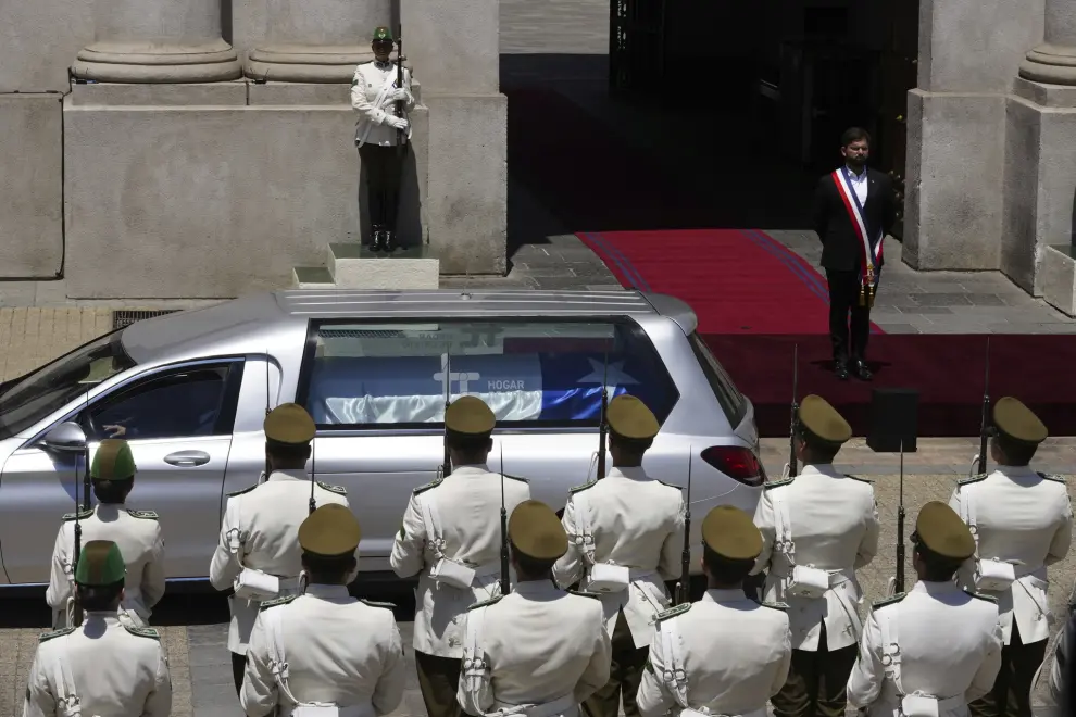 Chilean President Gabriel Boric watches the hearse carrying the remains of former President Sebastian Pinera drive past La Moneda presidential palace to the cemetery during a state funeral procession in Santiago, Chile, Friday, Feb. 9, 2024. The two-time former president died on Feb. 6 in a helicopter crash. He was 74. (AP Photo/Esteban Felix)