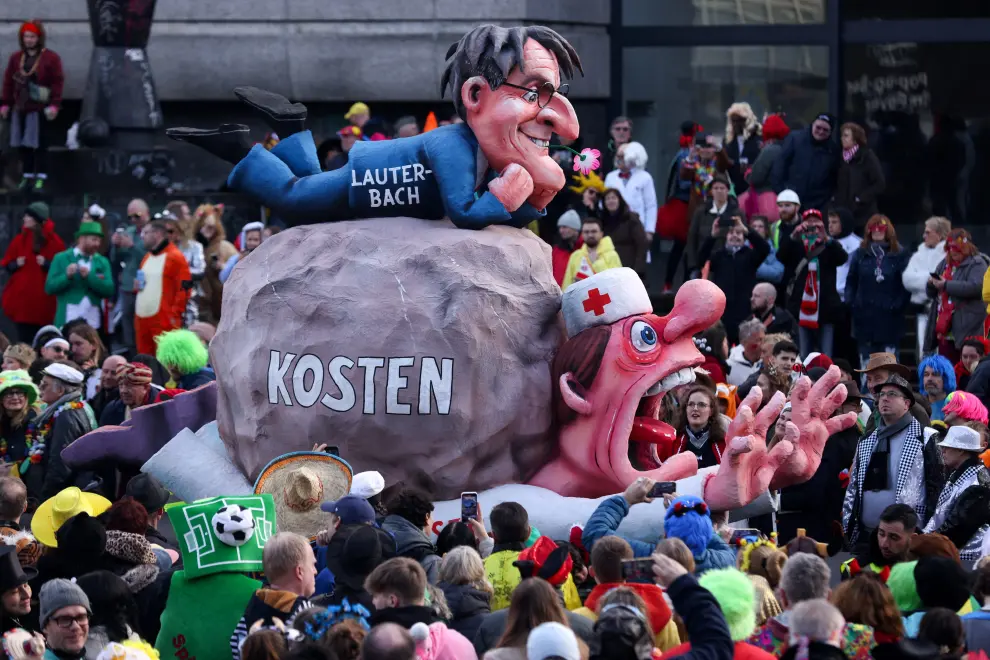 People stand around a carnival float depicting climate change, war, and the media, at the traditional Rosenmontag Rose Monday carnival parade in Dusseldorf, Germany, February 12, 2024. REUTERS/Thilo Schmuelgen [[[REUTERS VOCENTO]]] GERMANY-CARNIVAL/ROSEMONDAY