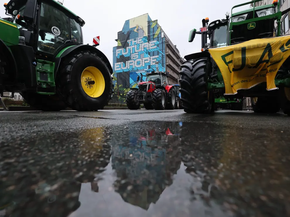 A farmer runs behind tires as he is sprayed by a water cannon during a protest of European farmers over price pressures, taxes and green regulation, on the day of an EU Agriculture Ministers meeting in Brussels, Belgium February 26, 2024. REUTERS/Yves Herman [[[REUTERS VOCENTO]]] EUROPE-FARMERS/PROTEST-BELGIUM