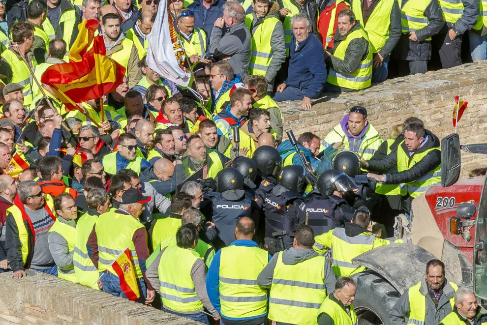 ZARAGOZA, 01/03/2024.- Un grupo de agricultores intenta romper el cordón policial mientras se concentran en los alrededores del Palacio de La Aljafería, sede de las Cortes de Aragón, este viernes en Zaragoza. EFE/ Javier Belver
