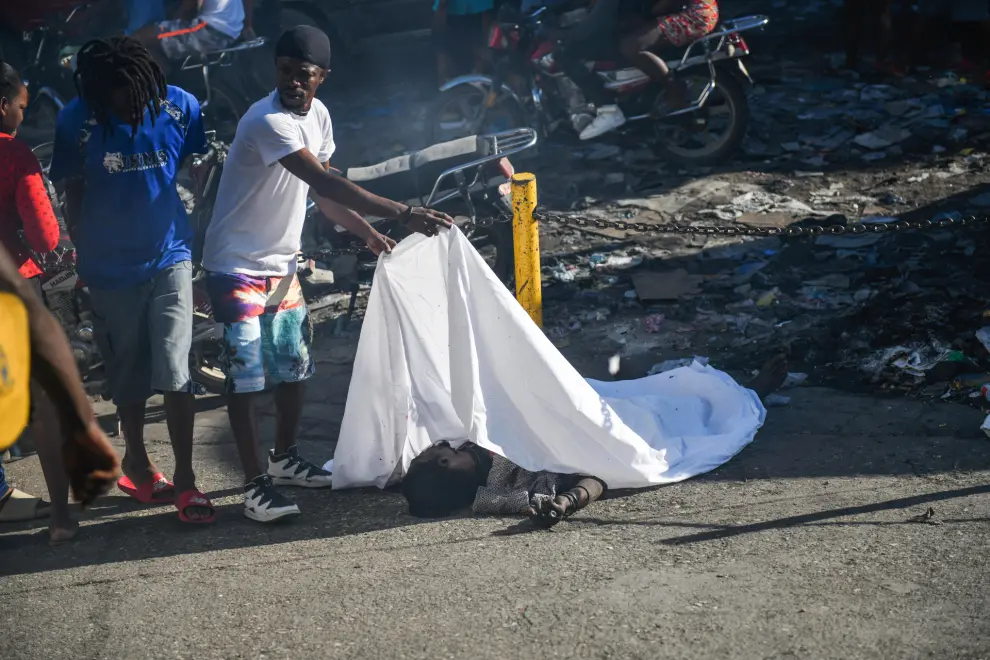 ATENCIÓN EDITORES: CONTENIDO GRÁFICO EXPLÍCITO - AME9715. PUERTO PRÍNCIPE (HAITÍ), 18/03/2024.- Un hombre cubre el cadáver de una persona en el suelo este lunes, en Puerto Príncipe (Haití). Doce cadáveres fueron encontrados este lunes en Petion-Ville, en las colinas de Puerto Príncipe, en circunstancias aún por aclarar, como la identidad de las víctimas, que no se descarta sean miembros de bandas armadas abatidos por la Policía Nacional. Los cuerpos, entre ellos el de una mujer, fueron hallados dispersos en plena vía, en los alrededores de una zona dedicada al comercio informal de alimentos y otros productos. EFE/ Johnson Sabin