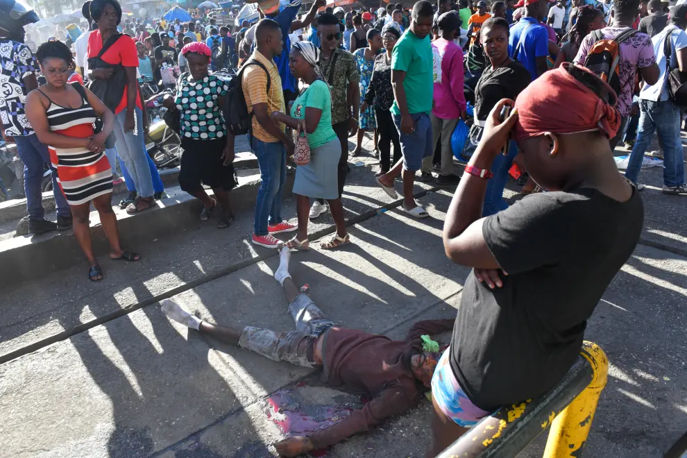 ATENCIÓN EDITORES: CONTENIDO GRÁFICO EXPLÍCITO - AME9715. PUERTO PRÍNCIPE (HAITÍ), 18/03/2024.- Varias personas rodean el cadáver de una persona en el suelo este lunes, en Puerto Príncipe (Haití). Doce cadáveres fueron encontrados este lunes en Petion-Ville, en las colinas de Puerto Príncipe, en circunstancias aún por aclarar, como la identidad de las víctimas, que no se descarta sean miembros de bandas armadas abatidos por la Policía Nacional. Los cuerpos, entre ellos el de una mujer, fueron hallados dispersos en plena vía, en los alrededores de una zona dedicada al comercio informal de alimentos y otros productos. EFE/ Johnson Sabin
