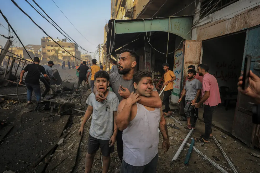 Un hombre sostiene a sus dos sobrinos mientras los palestinos buscan víctimas de un ataque israelí contra un edificio residencial en la ciudad de Gaza, el 25 de octubre de 2023
