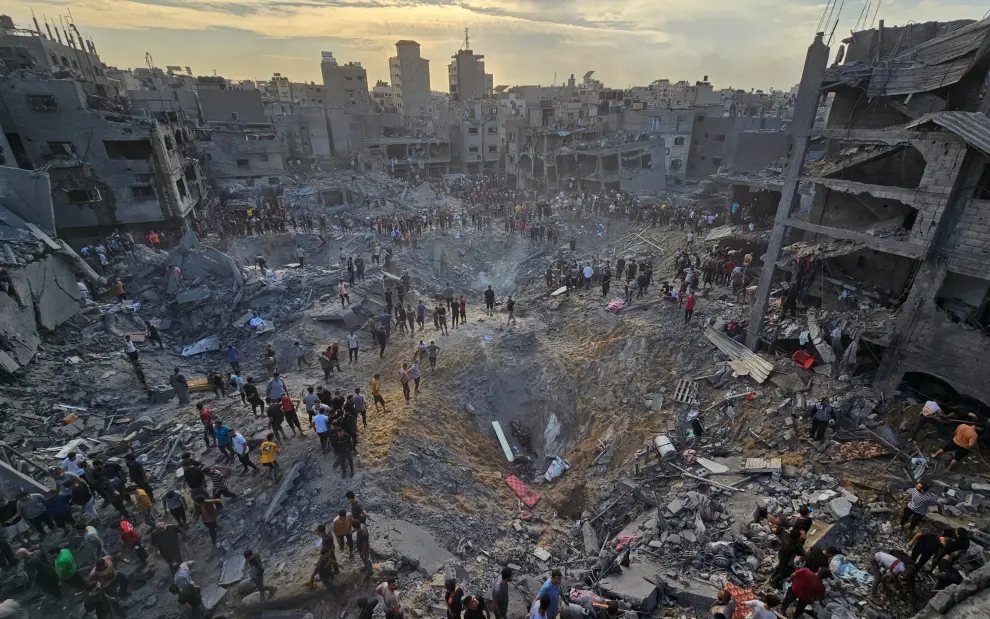 Los palestinos buscan víctimas en medio de profundos cráteres llenos de hormigón roto y metal retorcido, después de los ataques aéreos israelíes contra el campo de refugiados de Jabalia en el norte de la Franja de Gaza, el 31 de octubre de 2023.