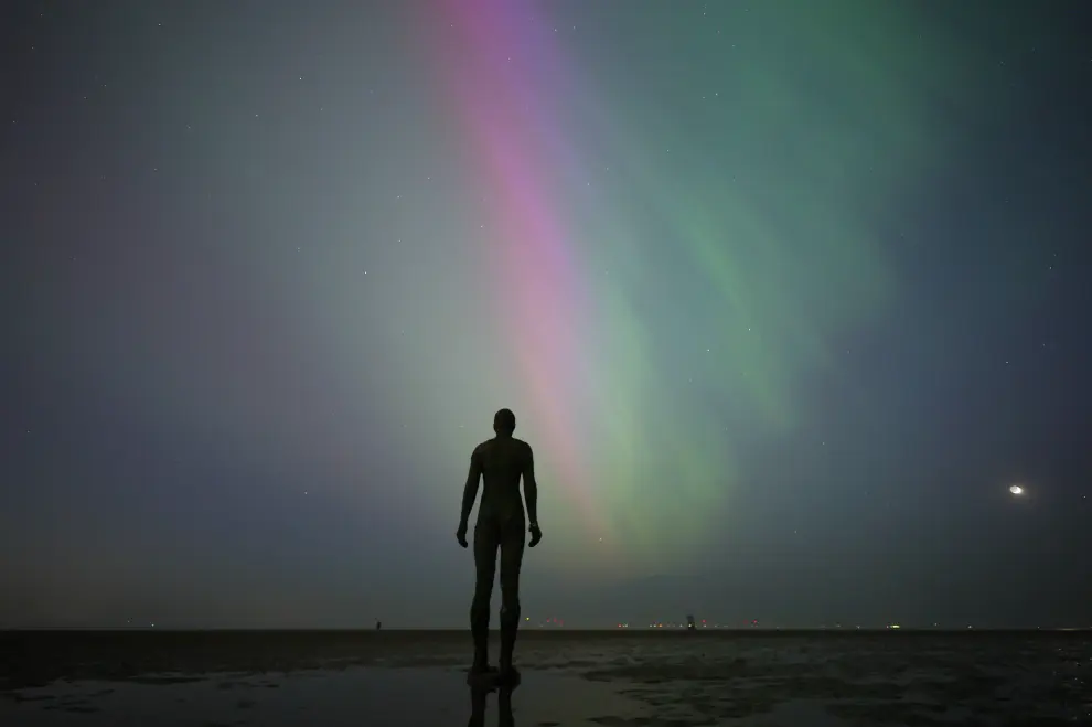 La aurora boreal visible frente a la escultura 'Another Place' de Anthony Gormley en Crosby, Gran Bretaña