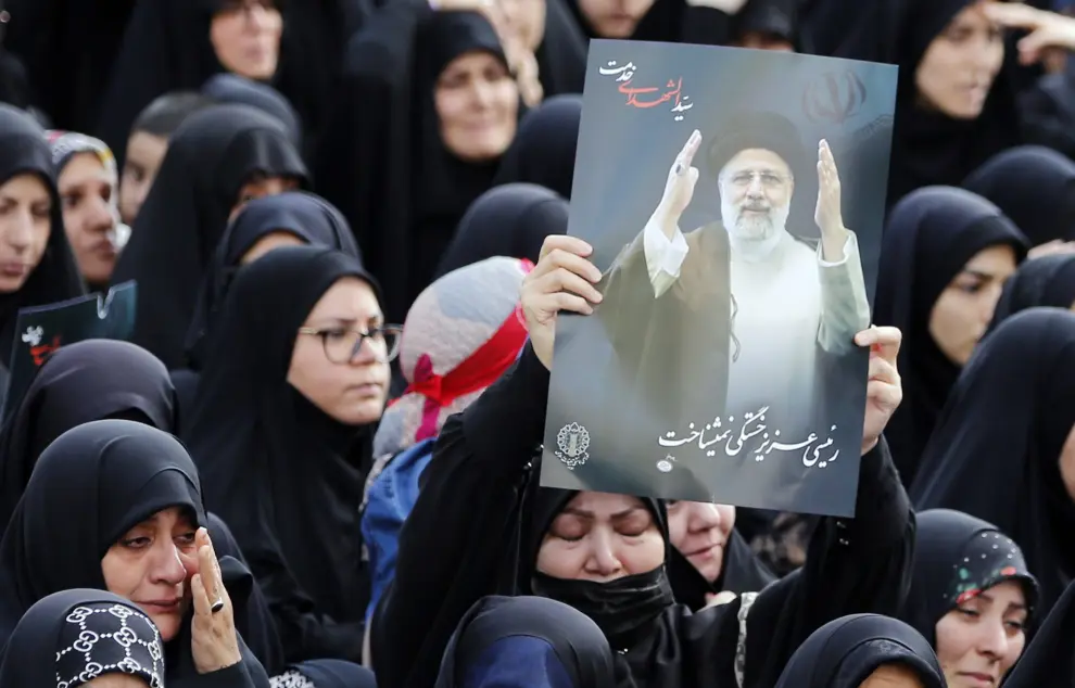 Iraníes sostienen carteles del fallecido presidente Ebrahim Raisi mientras participan en una ceremonia de luto en Teherán