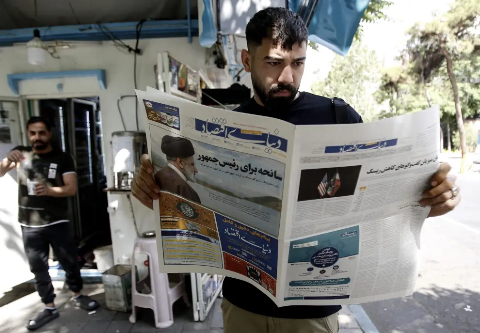Un iraní lee un periódico que informa sobre el accidente del helicóptero del presidente iraní, en un quiosco en Teherán