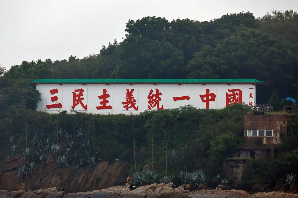 Un cartel anticomunista que dice 'unificar China con los Tres Principios del Pueblo' se ve en la isla Da-dan, cerca de la frontera marítima entre Taiwán y China