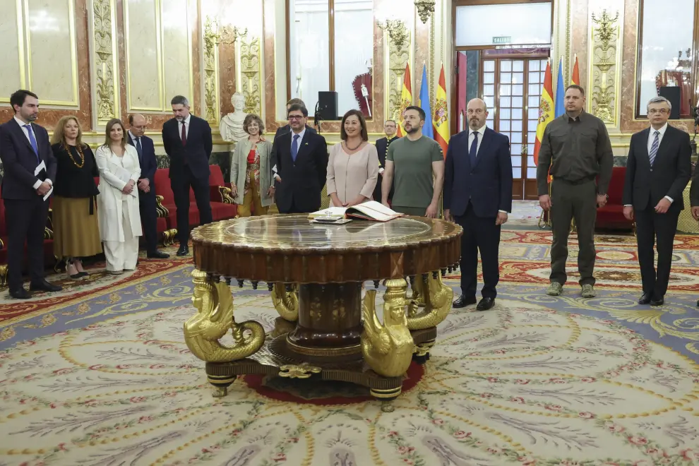 El presidente ucraniano, Volodímir Zelenski (c), firma el libro de visitas en el Congreso de los Diputados antes de su reunión con la presidenta del Congreso, Francina Armengol