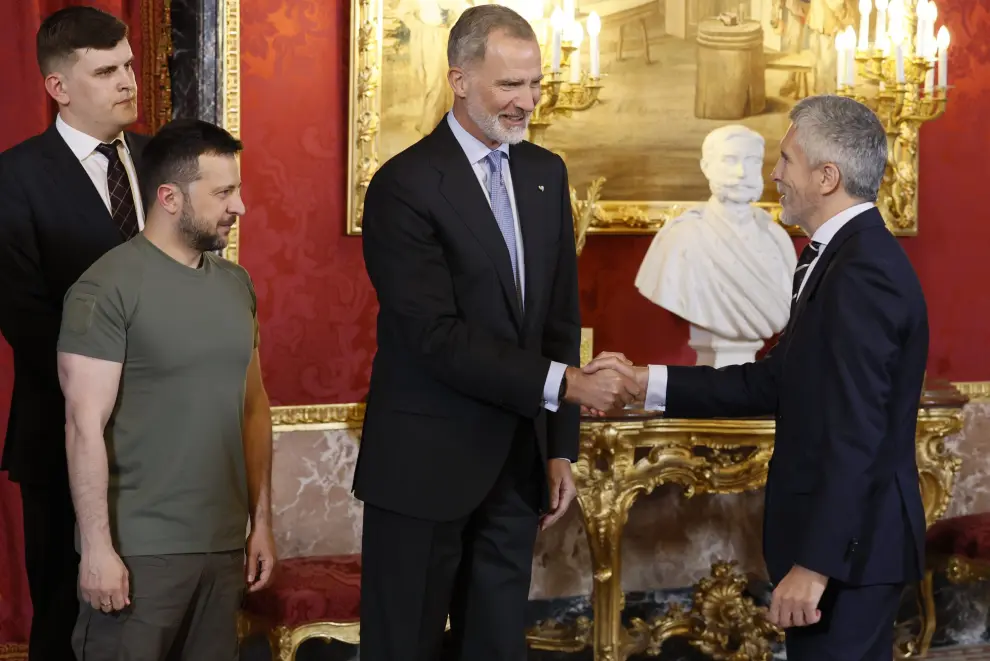 El rey Felipe VI, junto al presidente de Ucrania, Volodímir Zelenski, saludan al ministro del Interior, Fernando Grande-Marlaska, a su llegada al almuerzo ofrecido en el Palacio Real