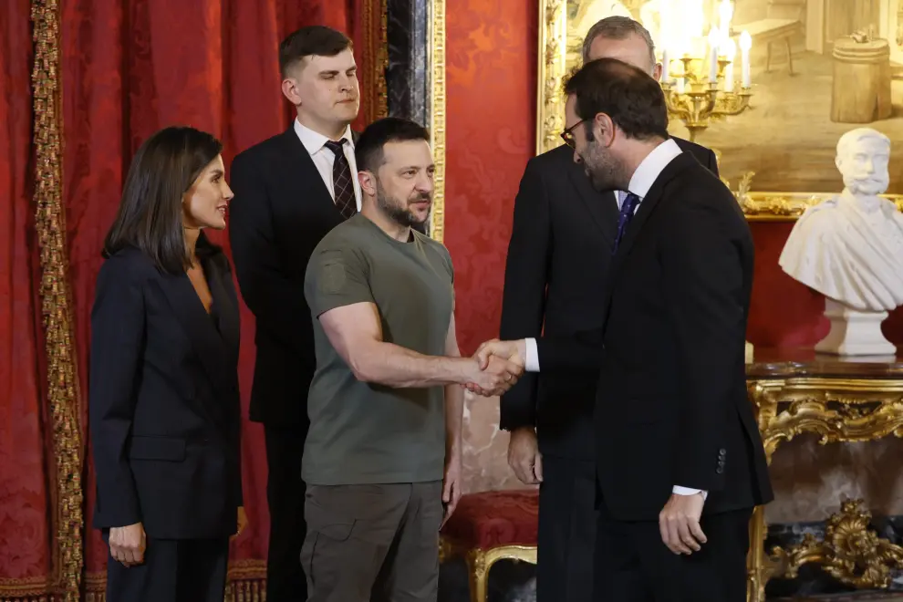 El rey Felipe VI, junto al presidente de Ucrania, Volodímir Zelenski (izda) saludan al ministro de Economía, Comercio y Empresa, Carlos Cuerpo, a su llegada al almuerzo ofrecido en el Palacio Real