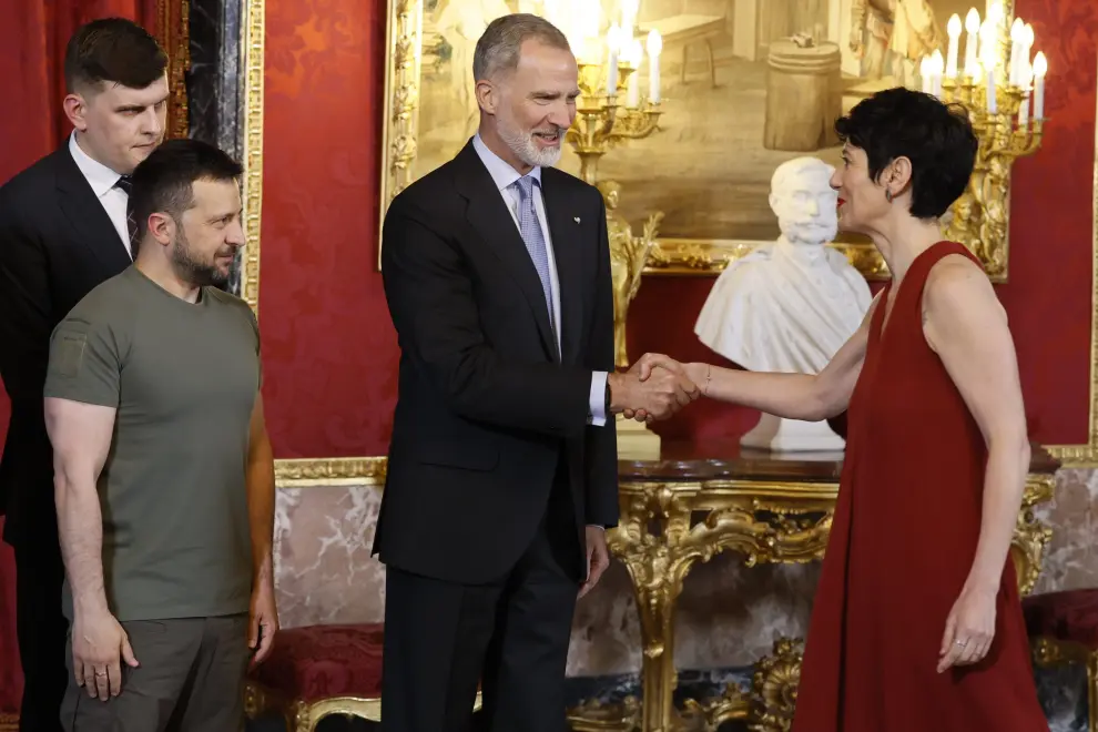 El rey Felipe VI, junto al presidente de Ucrania, Volodímir Zelenski (izda) saludan a la ministra de Inclusión, Seguridad Social y Migraciones, Elma Saiz, a su llegada al almuerzo ofrecido en el Palacio Real