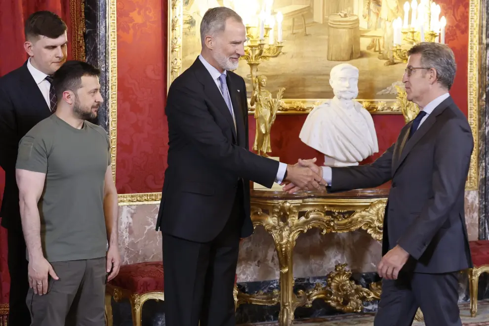 El rey Felipe VI, junto al presidente de Ucrania, Volodímir Zelenski (izda) saludan al líder del PP, Alberto Núñez Feijóo, a su llegada al almuerzo ofrecido en el Palacio Real