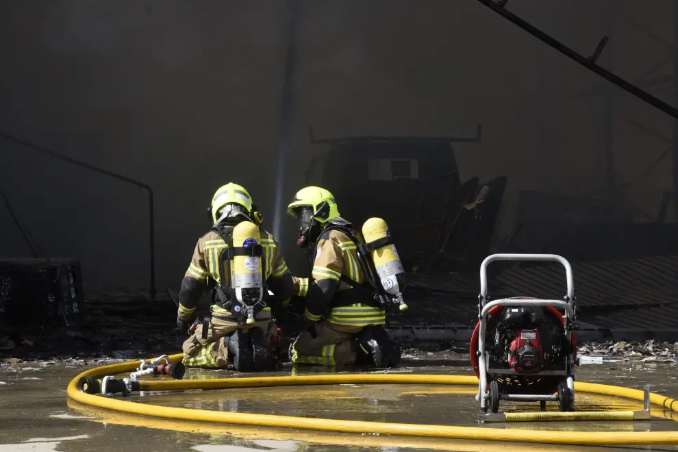 Varias dotaciones de bomberos trabajan en la extinción de un virulento incendio que ha destruido dos naves en el polígono Monzú de Huesca, una de ellas de residuos y otra de construcción.
