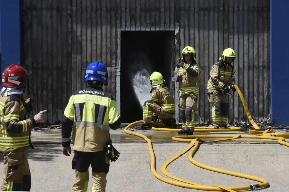 Varias dotaciones de bomberos trabajan en la extinción de un virulento incendio que ha destruido dos naves en el polígono Monzú de Huesca, una de ellas de residuos y otra de construcción.