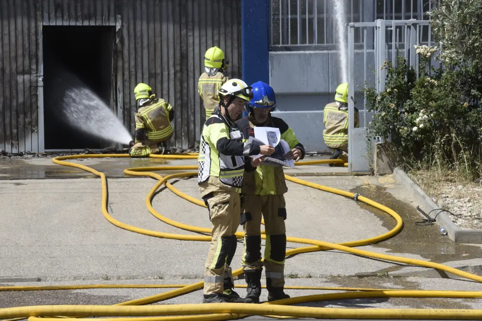 Varias dotaciones de bomberos trabajan en la extinción de un virulento incendio que ha destruido dos naves en el polígono Monzú de Huesca, una de ellas de residuos y otra de construcción.