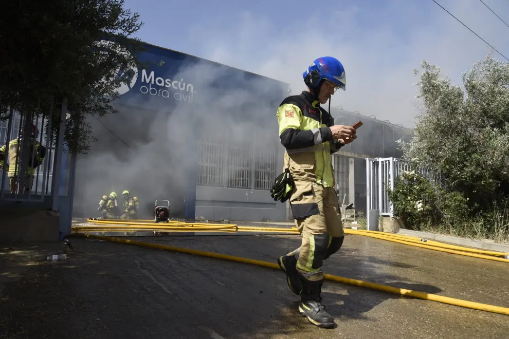 Varias dotaciones de bomberos trabajan en la extinción de un virulento incendio que ha destruido dos naves en el polígono Monzú de Huesca, una de ellas de residuos y otra de construcción.