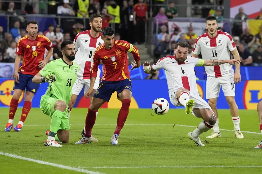 Georgia's Guram Kashia, right, reaches for the ball next to Spain's Alvaro Morata (7) goalkeeper Giorgi Mamardashvili, left, during a round of sixteen match between Spain and Georgia at the Euro 2024 soccer tournament in Cologne, Germany, Sunday, June 30, 2024. (AP Photo/Martin Meissner)