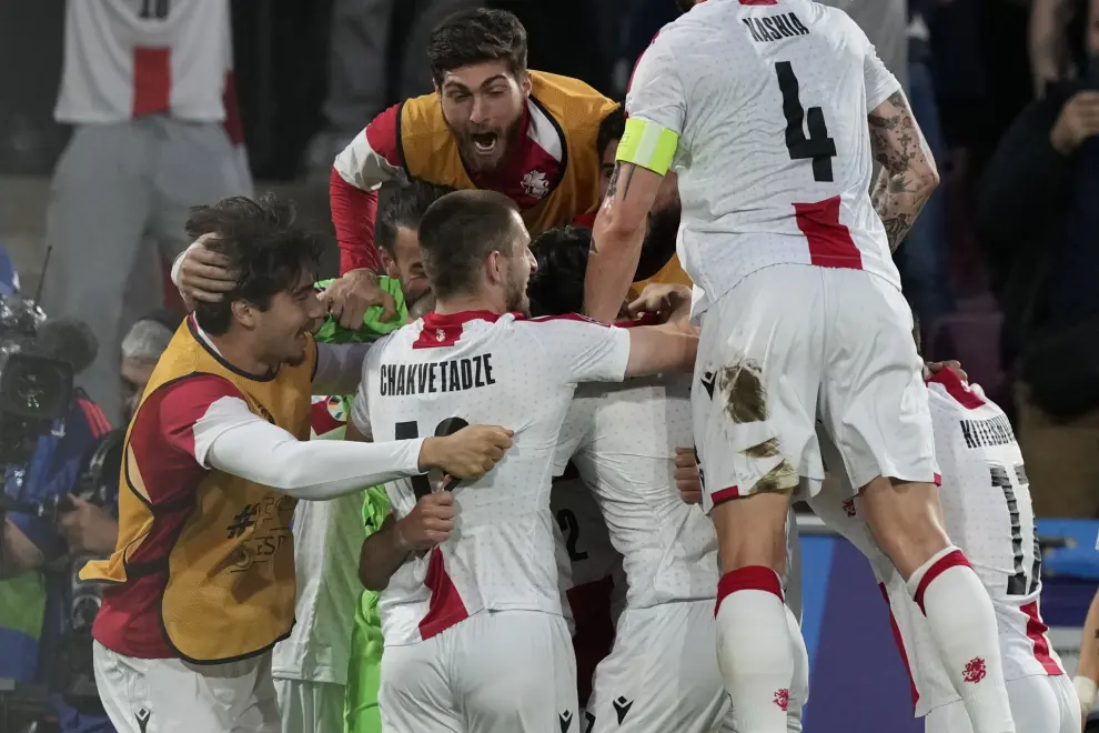 Georgia's players celebrate after forcing an own goal by Spain's Robin Le Normand during a round of sixteen match at the Euro 2024 soccer tournament in Cologne, Germany, Sunday, June 30, 2024. (AP Photo/Frank Augstein)