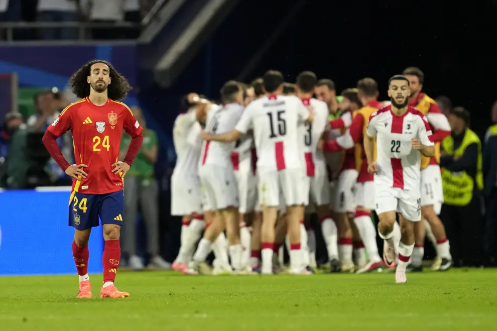 Spain's Marc Cucurella walks as Georgia players celebrate the opening goal during a round of sixteen match between Spain and Georgia at the Euro 2024 soccer tournament in Cologne, Germany, Sunday, June 30, 2024. (AP Photo/Darko Vojinovic)