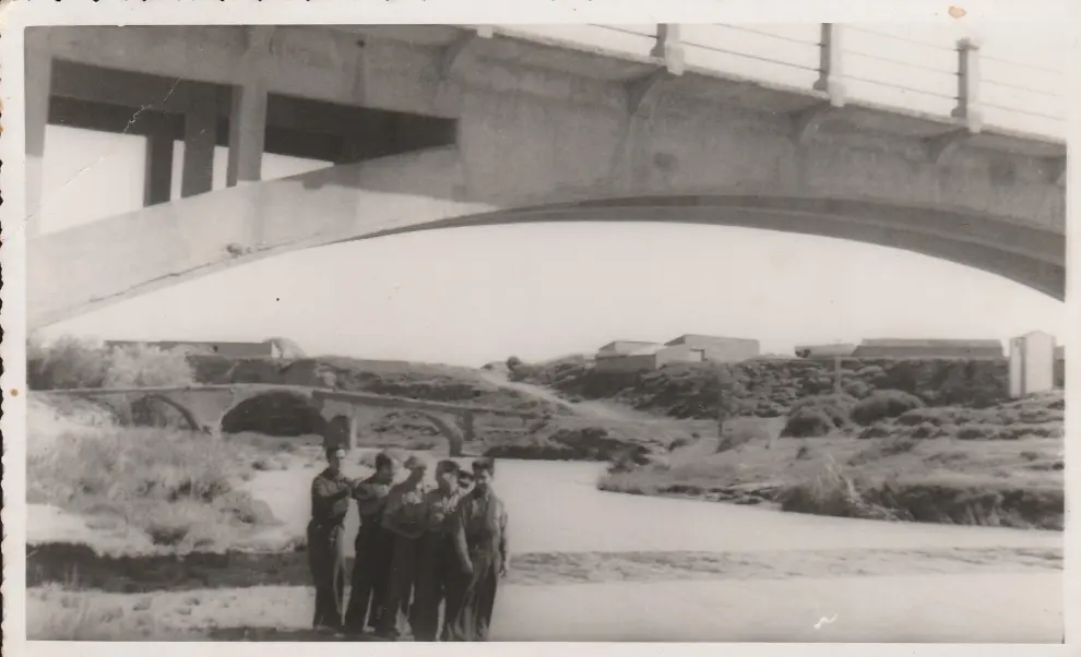 Conductores de ambulancia posando junto al río Flumen a su paso por Poleñino, con los dos puentes, nuevo y viejo, de fondo