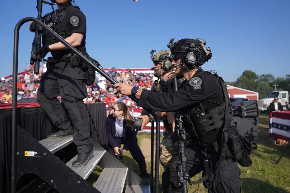 U.S. Secret Service agents rush to the stage as Republican presidential candidate former President Donald Trump is surrounded by U.S. Secret Service agents at a campaign rally, Saturday, July 13, 2024, in Butler, Pa. (AP Photo/Evan Vucci)