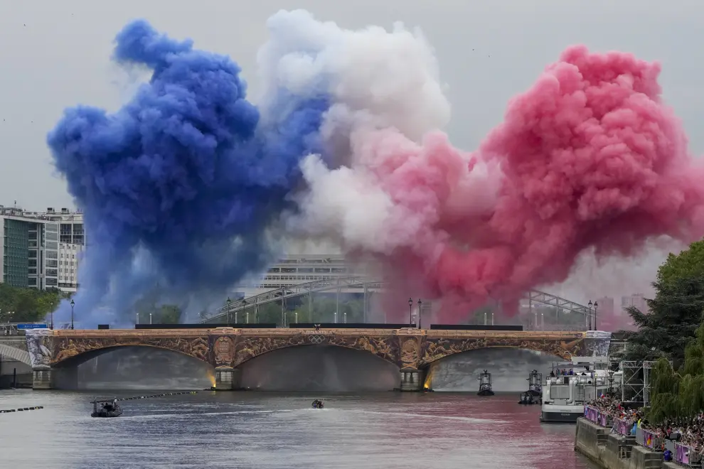 Ceremonial smoke in the colors of the France flag appear over the Seine River in Paris, France, during the opening ceremony of the 2024 Summer Olympics, Friday, July 26, 2024. (AP Photo/Matthias Schrader)