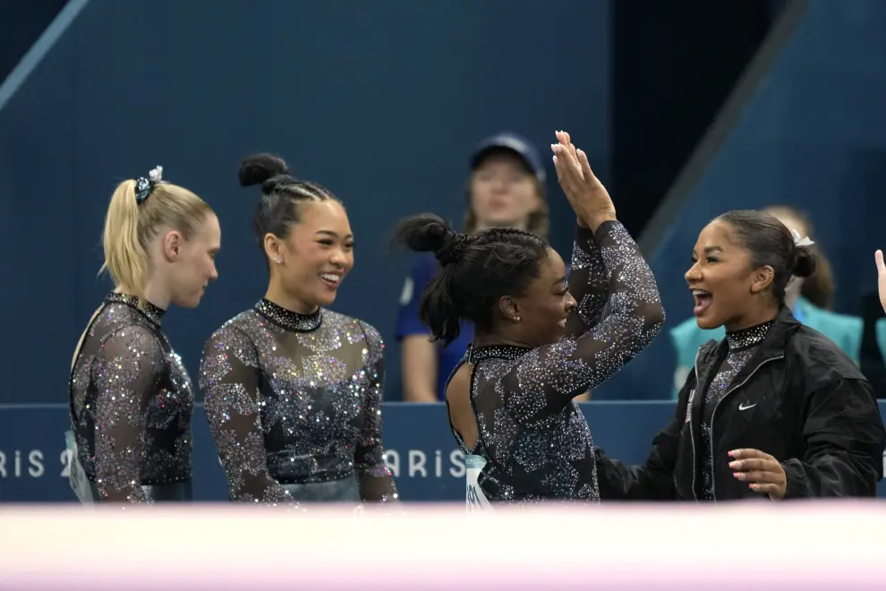 Jade Carey, from left, Hezly Rivera, Simone Biles and Jordan Chiles, right, of the United States smile after Biles competed on the balance beam during a women's artistic gymnastics qualification round at the 2024 Summer Olympics, Sunday, July 28, 2024, in Paris, France. (AP Photo/Charlie Riedel)