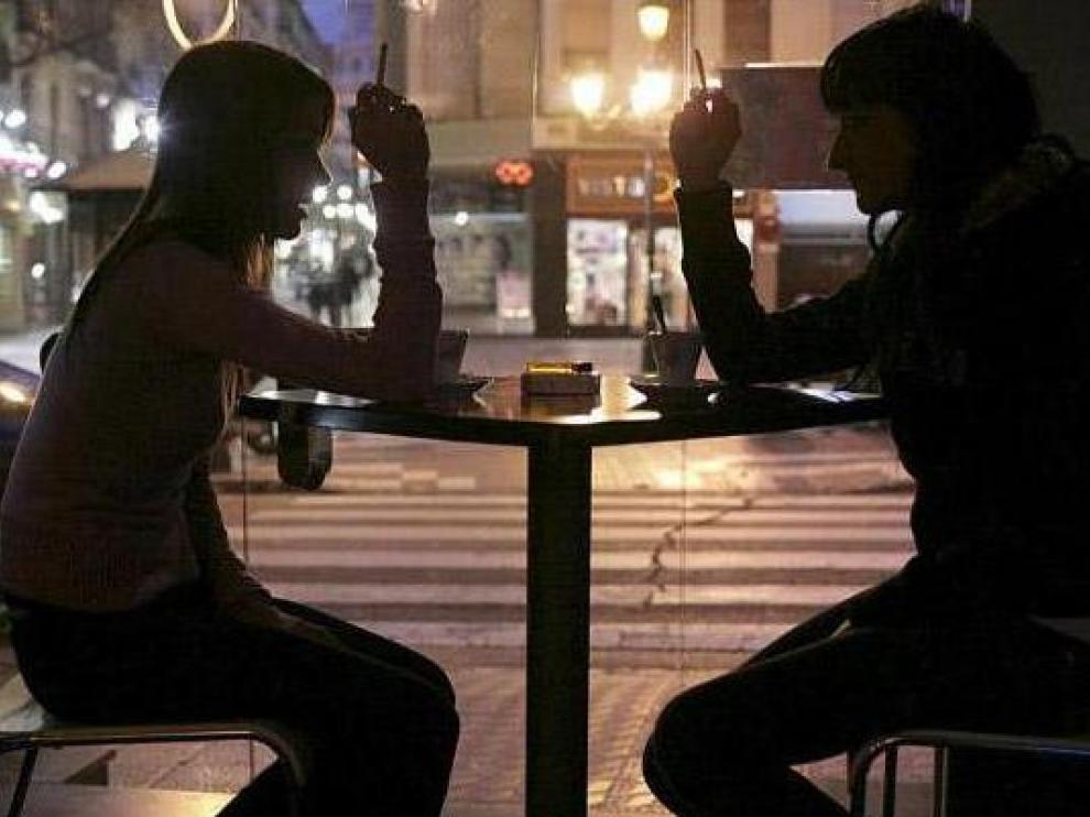 Dos clientes fuman en una cafetería del centro de Zaragoza mientras toman un café
