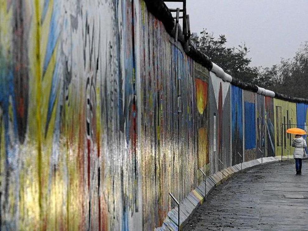 Una mujer pasea junto a un segmento del East Side Gallery de Berlín, el tramo más largo que aún queda en pie del muro.