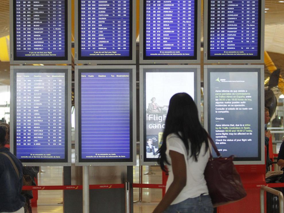Una mujer observa el panel de salidas de vuelos en la T4 de Barajas.