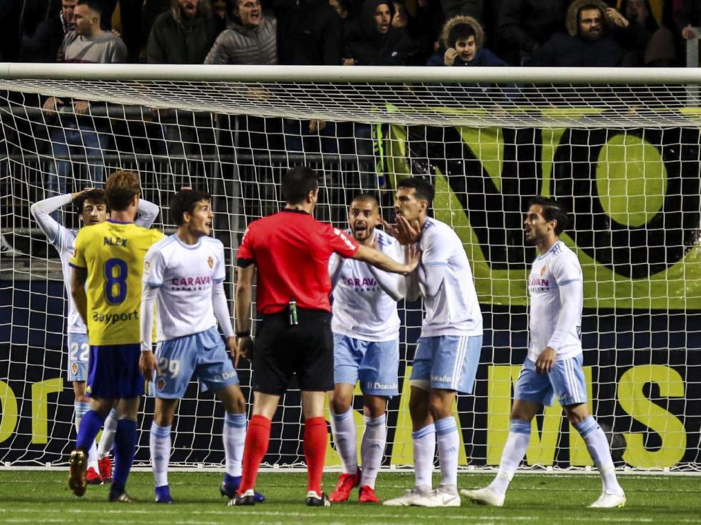 Los jugadores del Real Zaragoza protestan a Díaz de Mera, árbitro del partido del pasado lunes en Cádiz, la decisión del penalti que supuso el 3-3 final ya con el tiempo concluido.