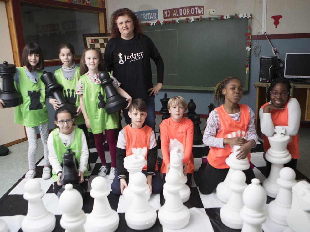 Escolares de primaria del CEIP Zalfonada de Zaragoza, con su maestra Miriam Monreal, tras disputar una partida de ajedrez en el tablero de lona con piezas gigantes