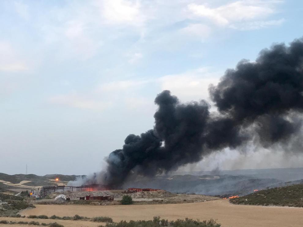 Los bomberos tratan de impedir que las llamas se extiendan por los cultivos que rodean la planta.